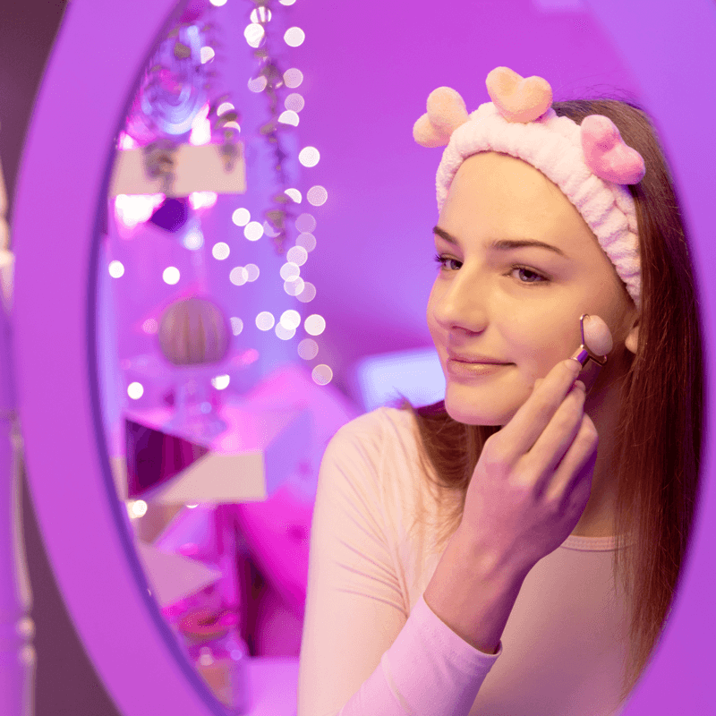 Mädchen mit TOPModel Haarband lächelt in den Spiegel und nutzt den TOPModel Face Roller