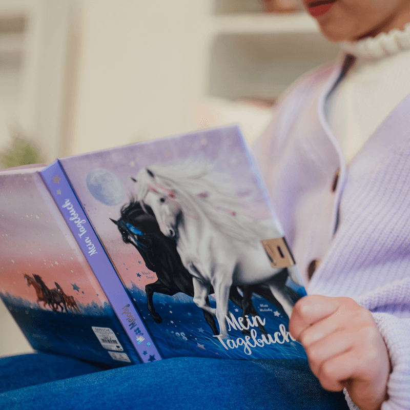 Miss Melody Tagebuch in Hand eines Mädchens mit lila Strickjacke