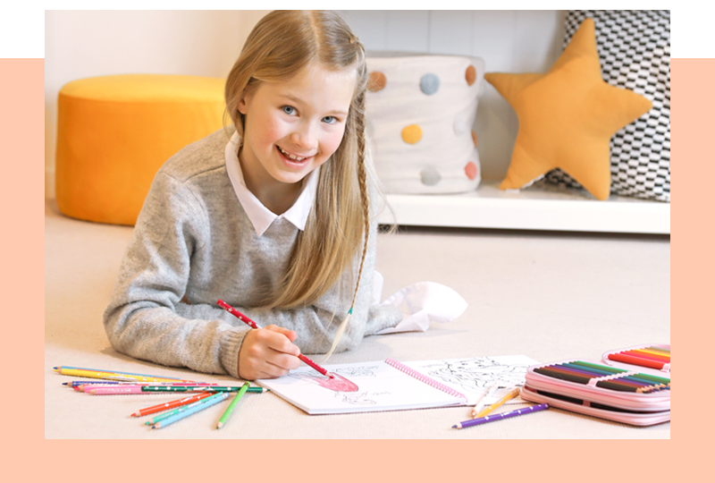 Lächelndes Mädchen malt im TOPModel Malbuch mit bunten Stiften