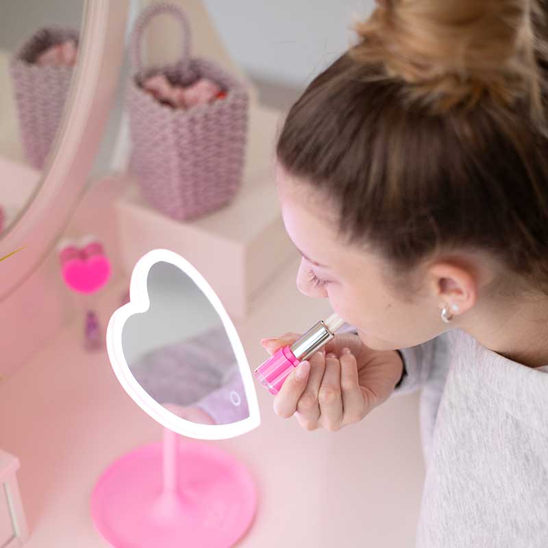 Mädchen mit TOPModel Beauty and Me Lipgloss vor einem Herz-Spiegel