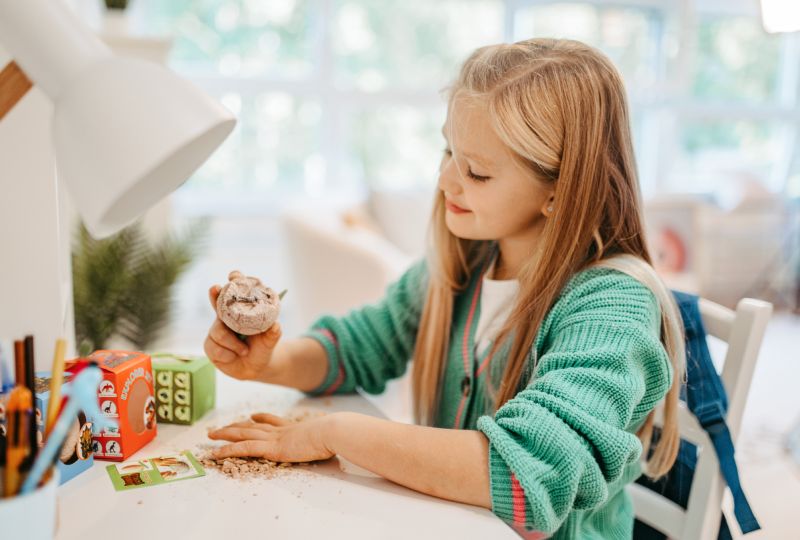 Girl Opens Dino World Discovery Egg at Desk