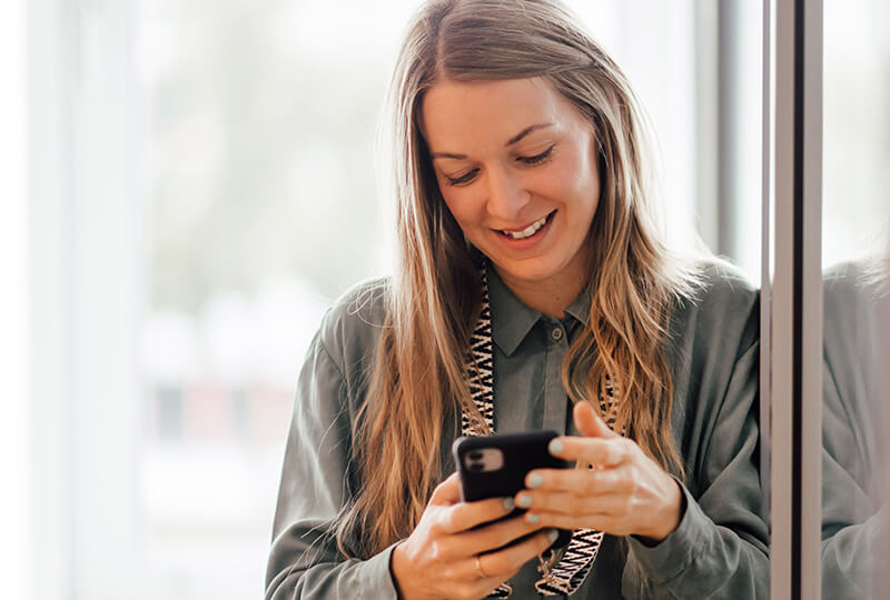 Empleada de medios sociales sonriendo a su smartphone