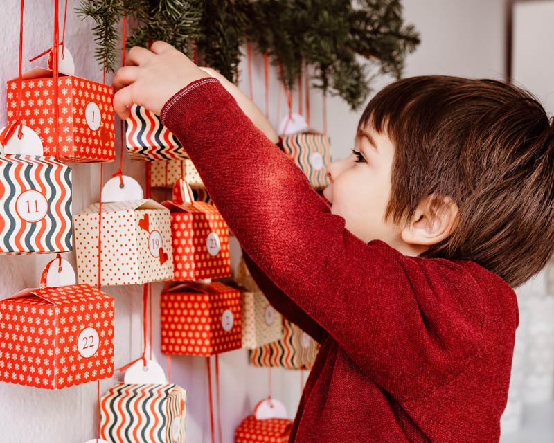 Kind öffnet freudig einen DIY Adventskalender