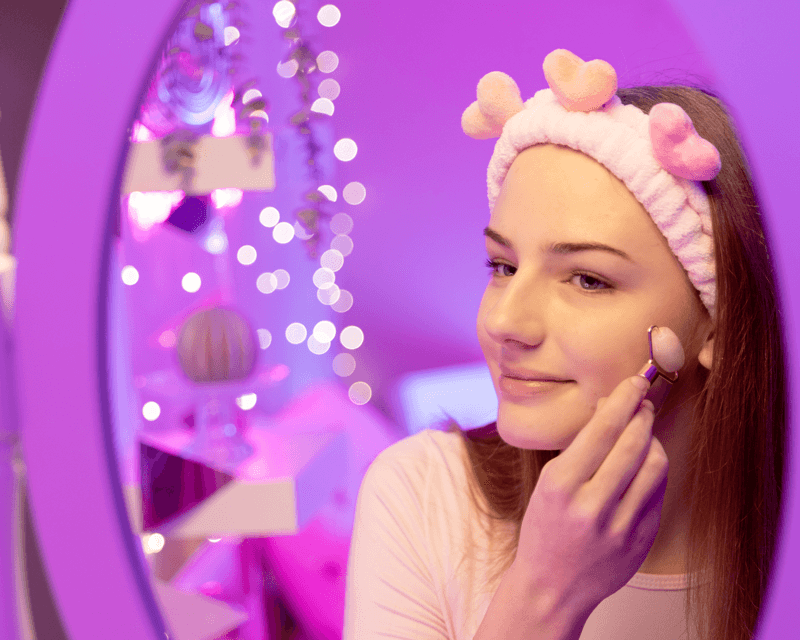 Mädchen mit TOPModel Haarband lächelt in den Spiegel und nutzt den TOPModel Face Roller