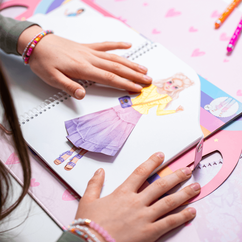 Kinderhände basteln im TOPModel Bastelbuch mit bunten Rücken und anderen Outfits