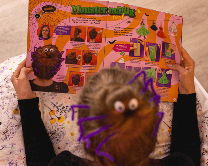Mädchen mit Spinnen-Frisur blättert in der Halloween-Ausgabe des TOPModel Magazins