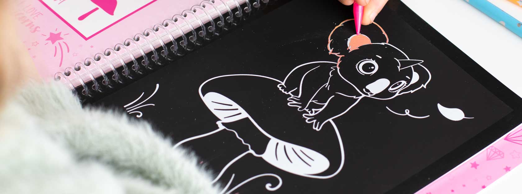 Kinderhand kritzelt im Ylvi Magic Scratch Buch ein Koala-Einhorn-Motiv