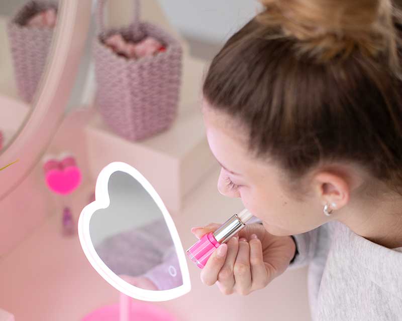 Mädchen mit TOPModel Beauty and Me Lipgloss vor einem Herz-Spiegel
