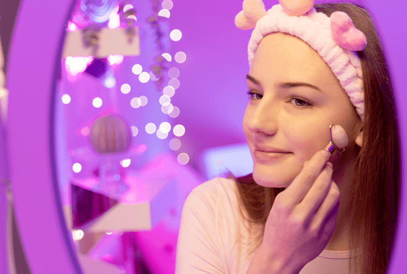 Mädchen mit TOPModel Haarband lächelt in den Spiegel und nutzt den TOPModel Face Roller