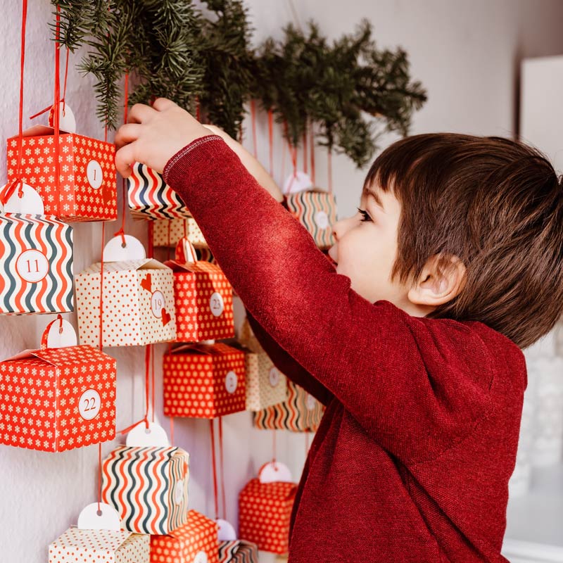 Junge packt freudig Adventskalender aus