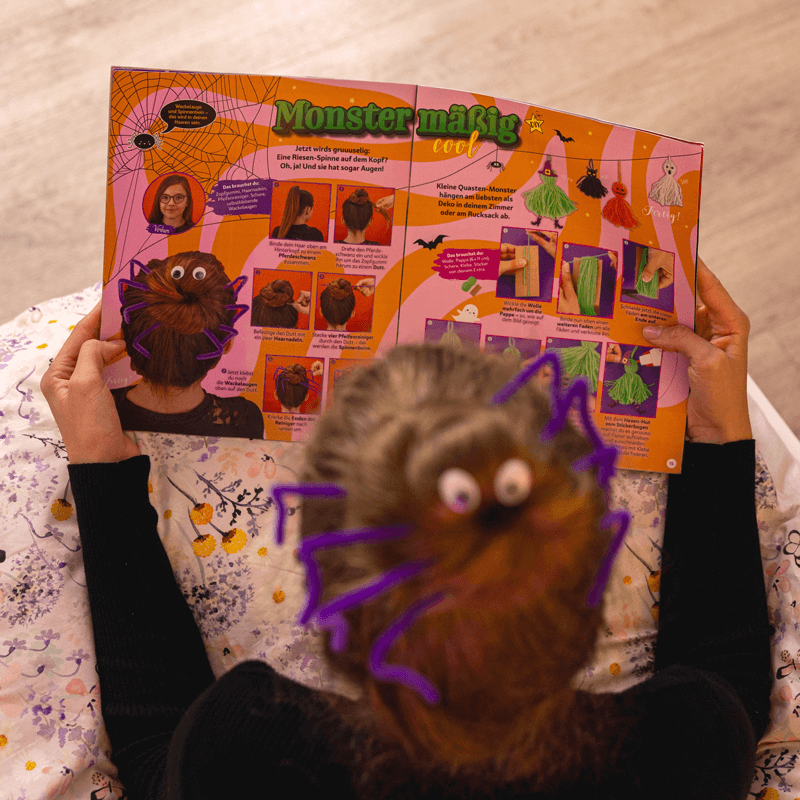 Mädchen mit Spinnen-Frisur blättert in der Halloween-Ausgabe des TOPModel Magazins