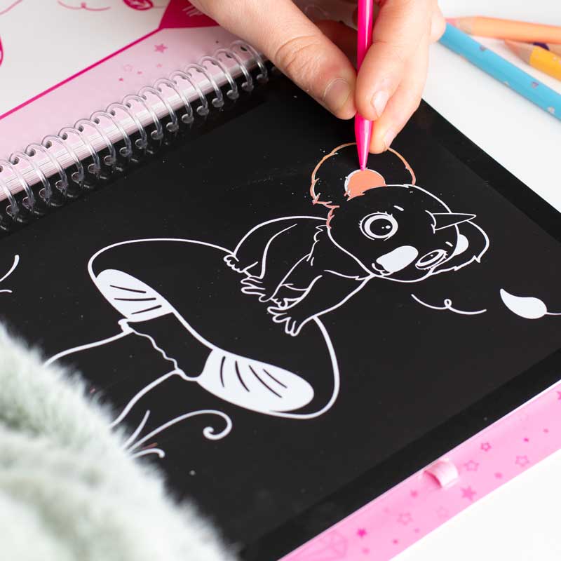 Kinderhand kritzelt im Ylvi Magic Scratch Buch ein Koala-Einhorn-Motiv