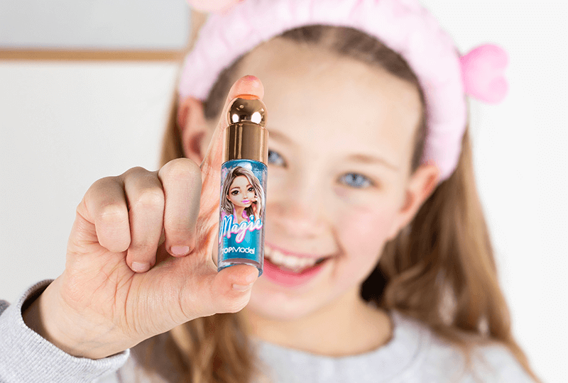 Mädchen mit rosa Haarband hält TOPModel Lipgloss ins Bild