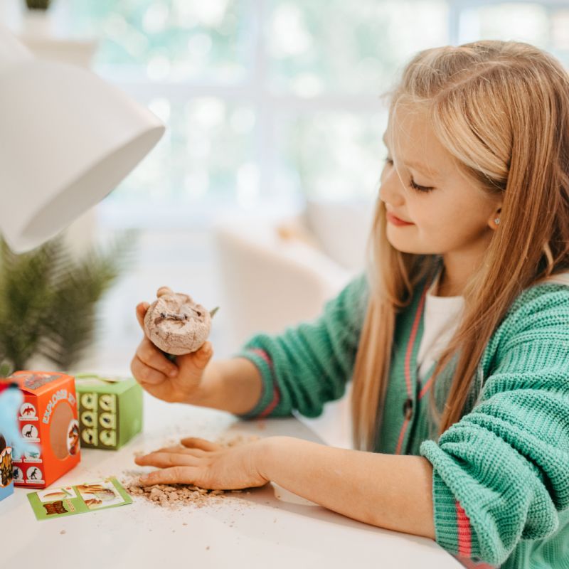 Mädchen spielt mit Dino World Entdecker-Ei am Schreibtisch