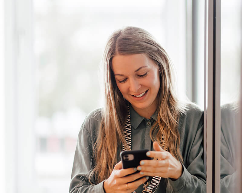 Freundlich lächelnde Depesche-Mitarbeiterin am Smarphone